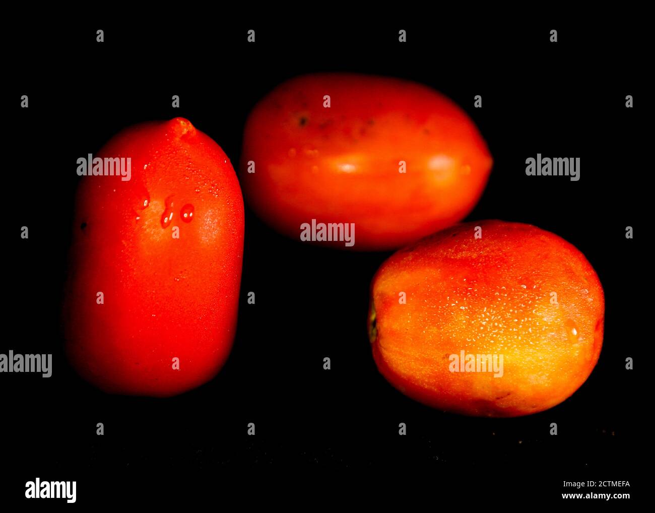 Three ripe red tomatoes isolated on black background Stock Photo