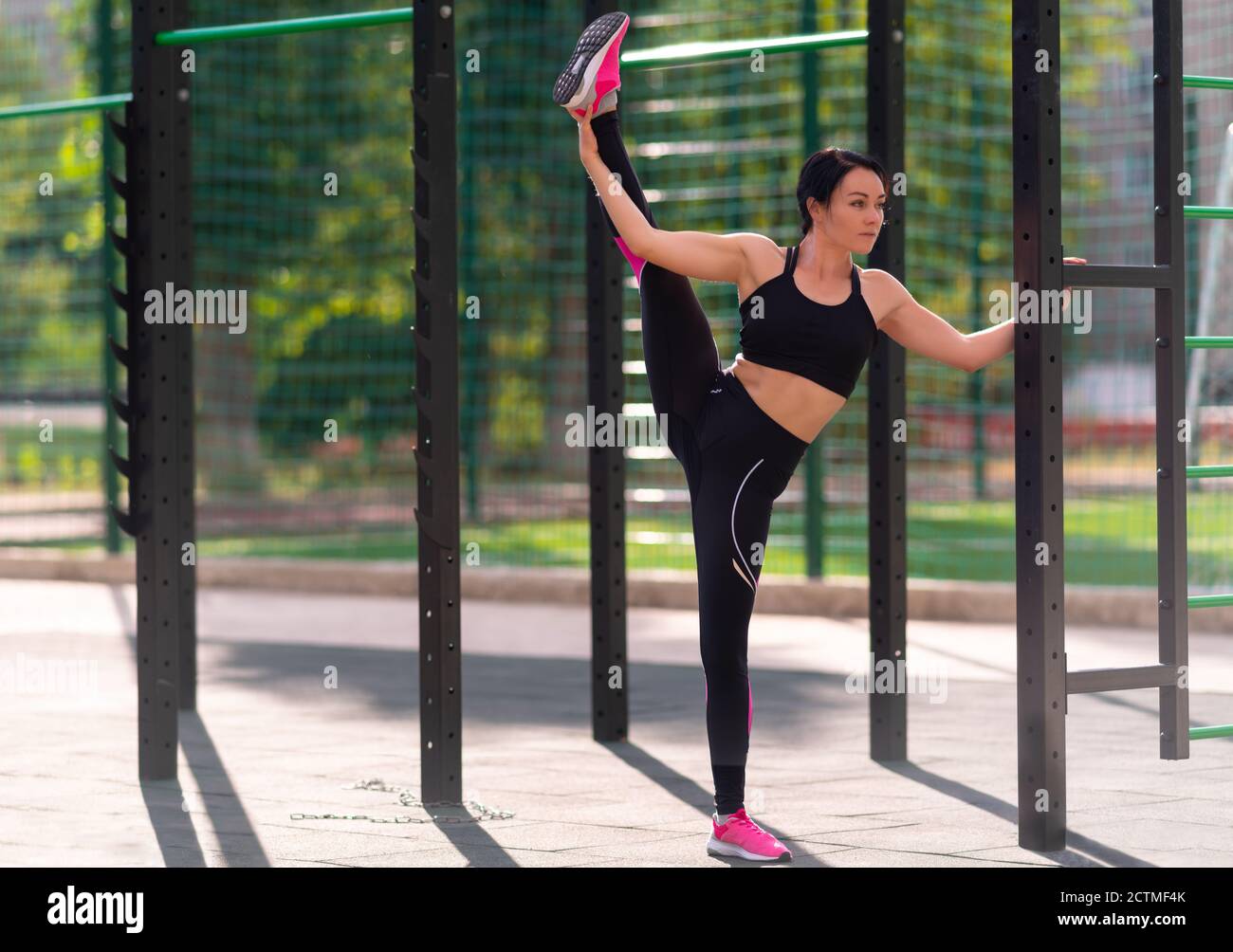 Supple young woman doing the vertical splits outdoors in an open air ...