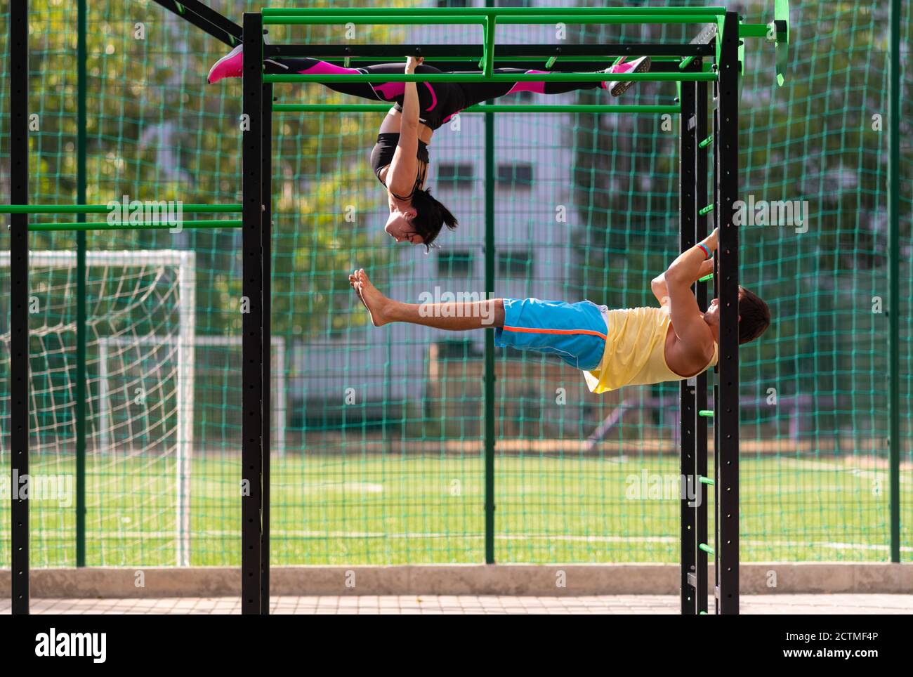 Young athletic couple working out on parallel bars and gym ladder at an ...