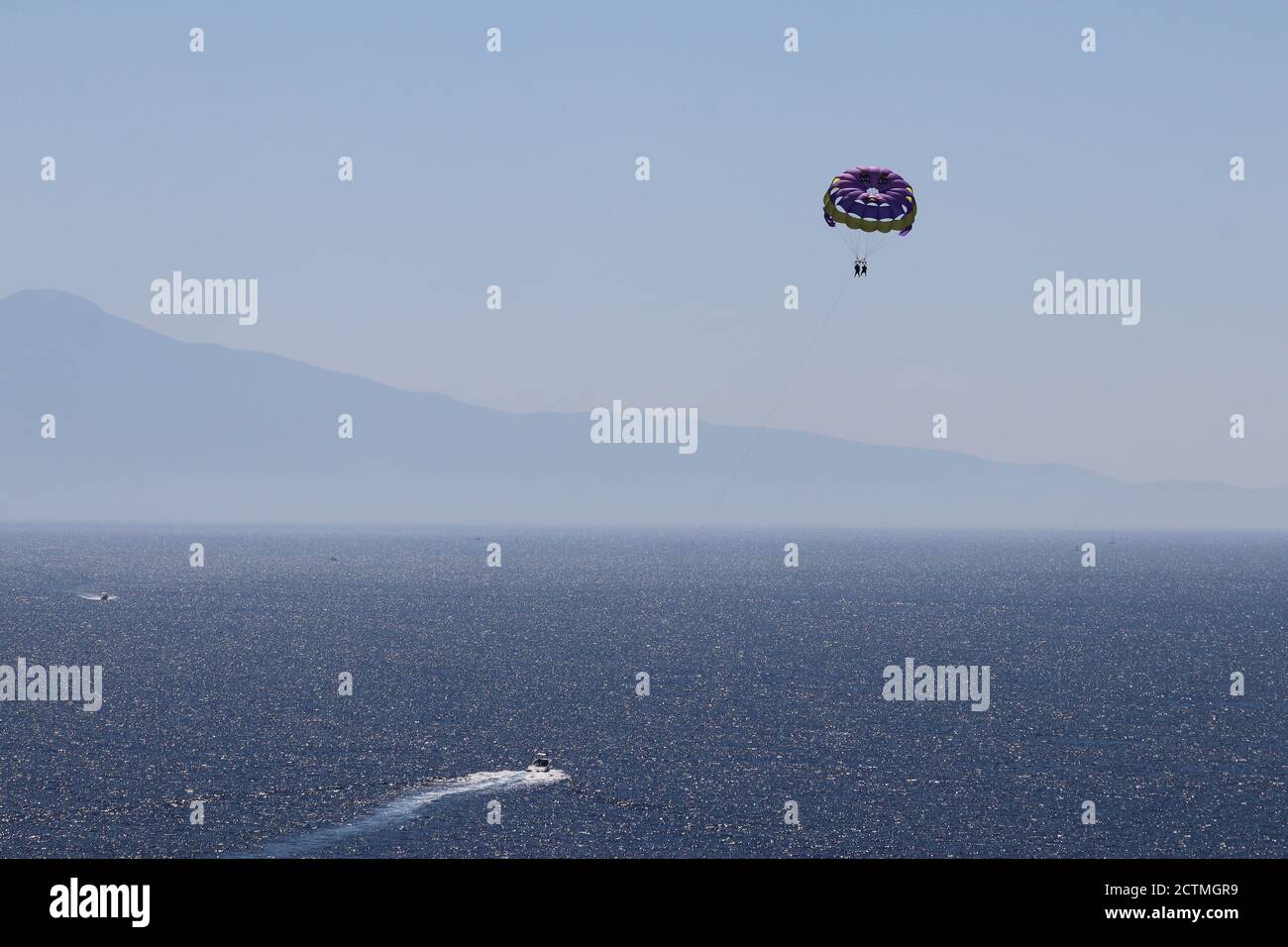 Parasailing on the sea, people flying on parachute on mountain and seascape background. Concept of vacation, extreme sports on a beach Stock Photo