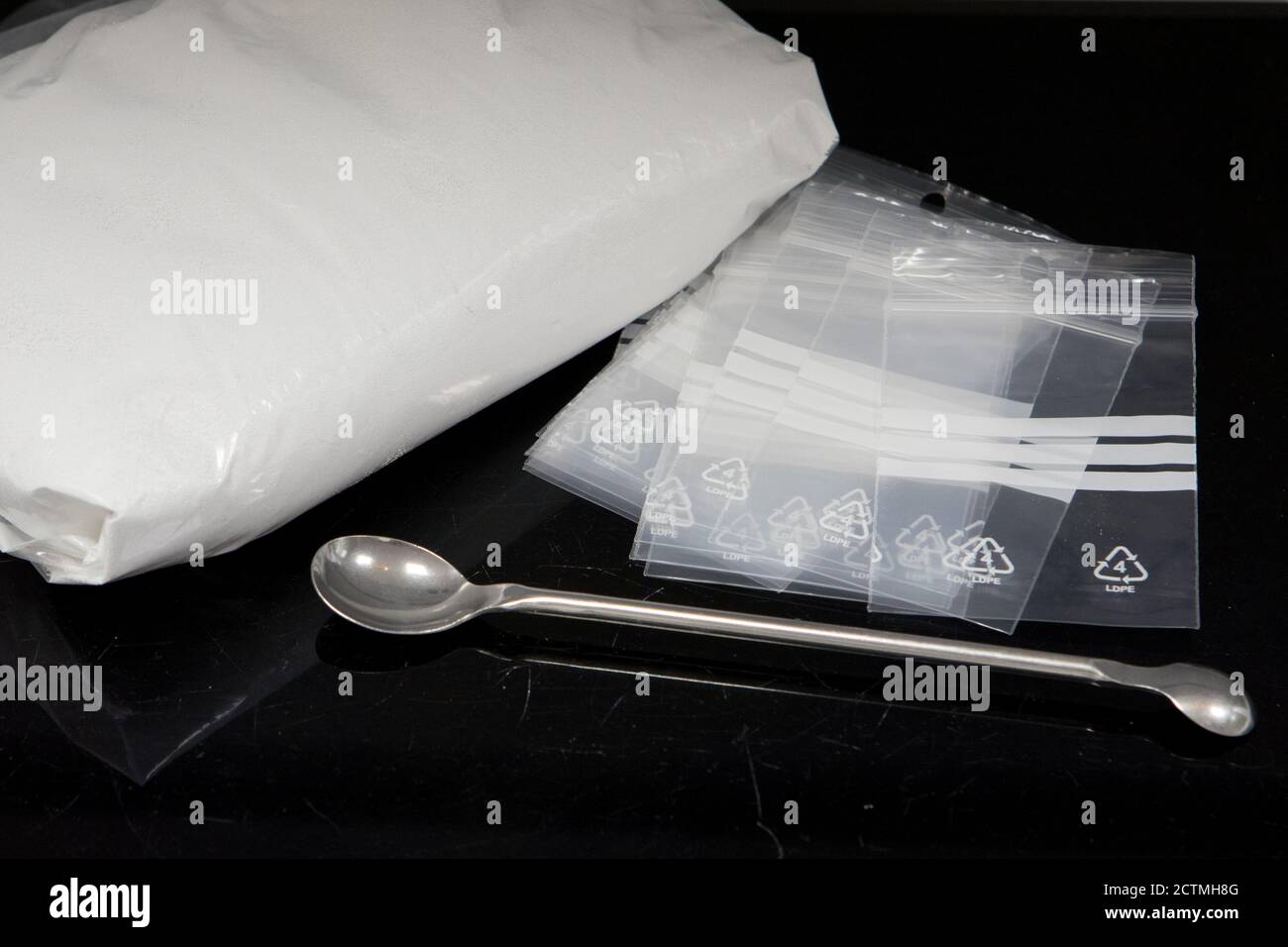 Drug dealing concept with large bag of white powder and several smaller deal bags Stock Photo