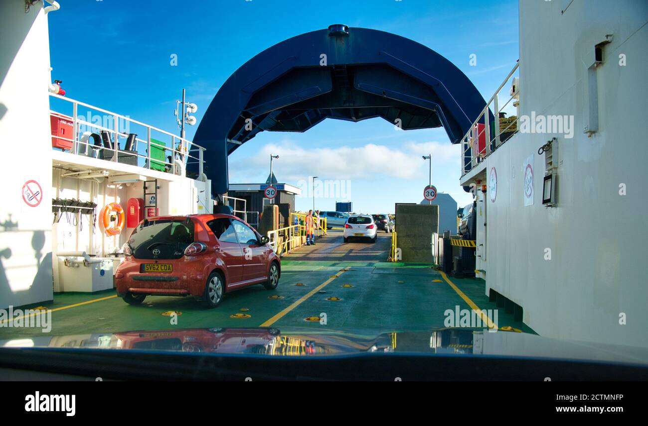 With the bow door raised, cars leave the inter-island ferry at the  Gutcher terminal on the island of Yell in Shetland, an archipelago of islands in h Stock Photo