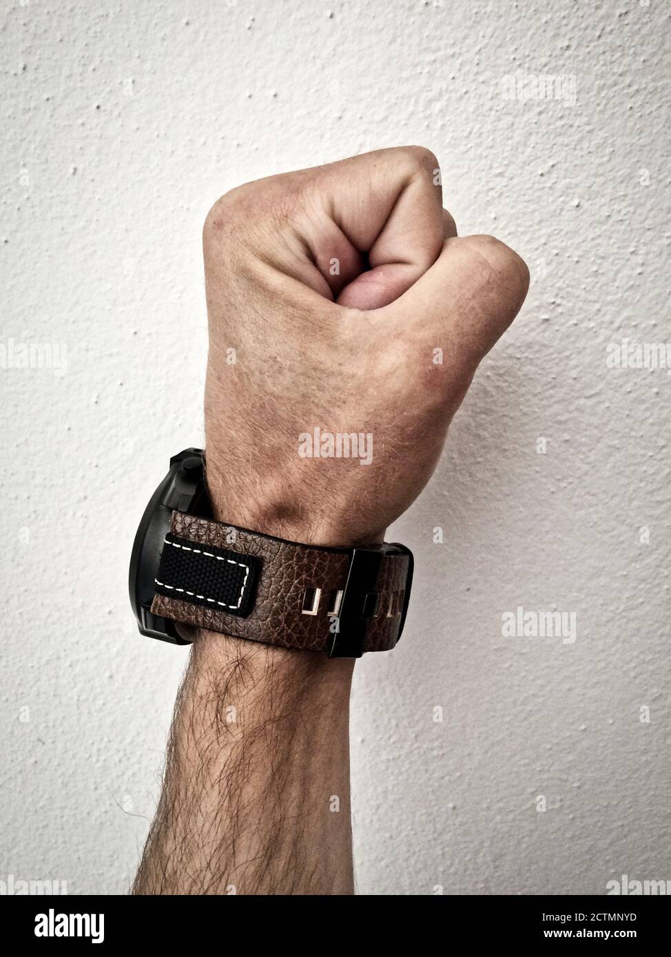 big watch on a white man's hand, make a fist, watch on the arm, part of the body, white skin, white background, pounding, hair on the arm, part of the Stock Photo