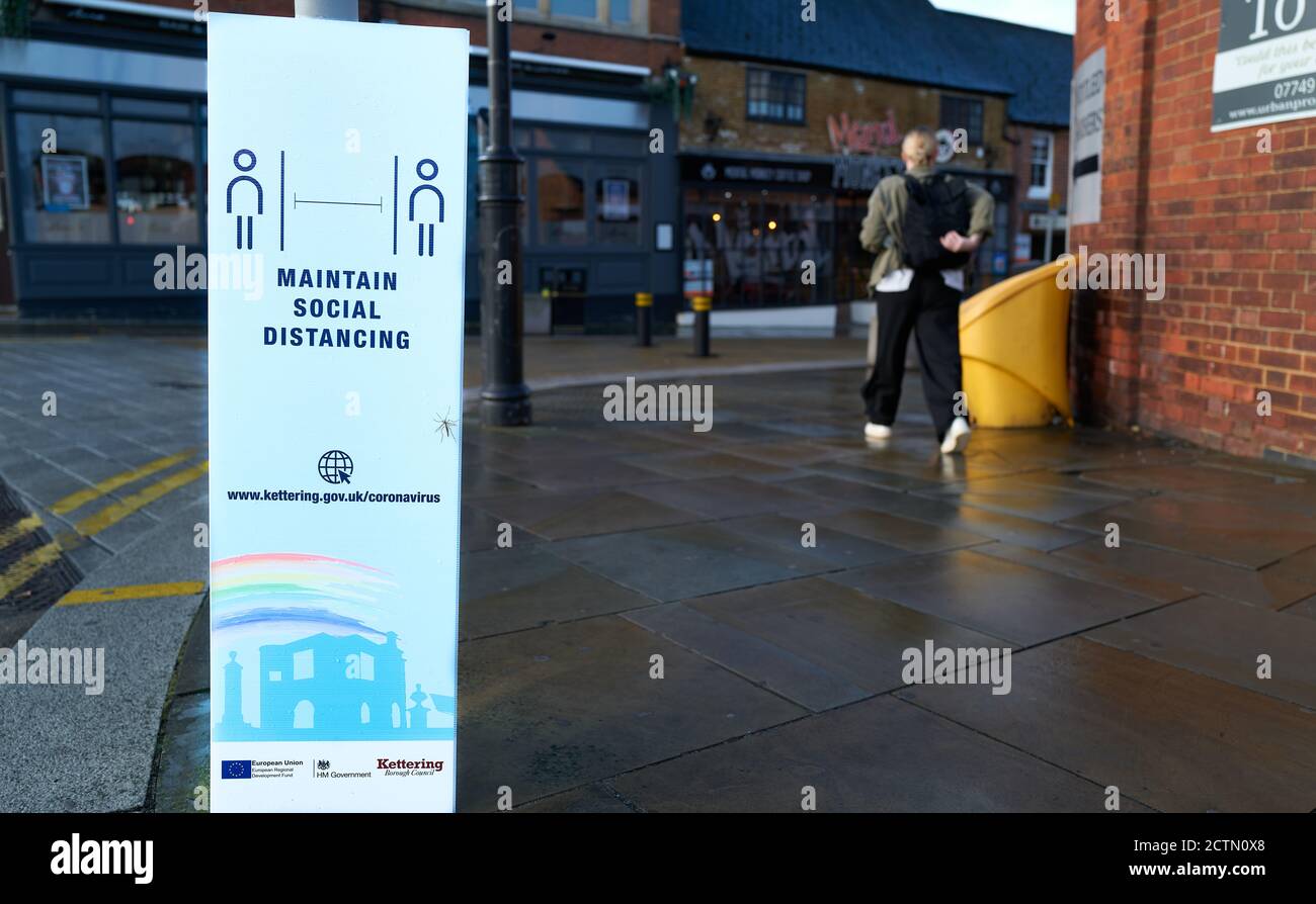 'Maintain social distancing' notice on the pavement outside a shop at Kettering, Northants, England. Stock Photo