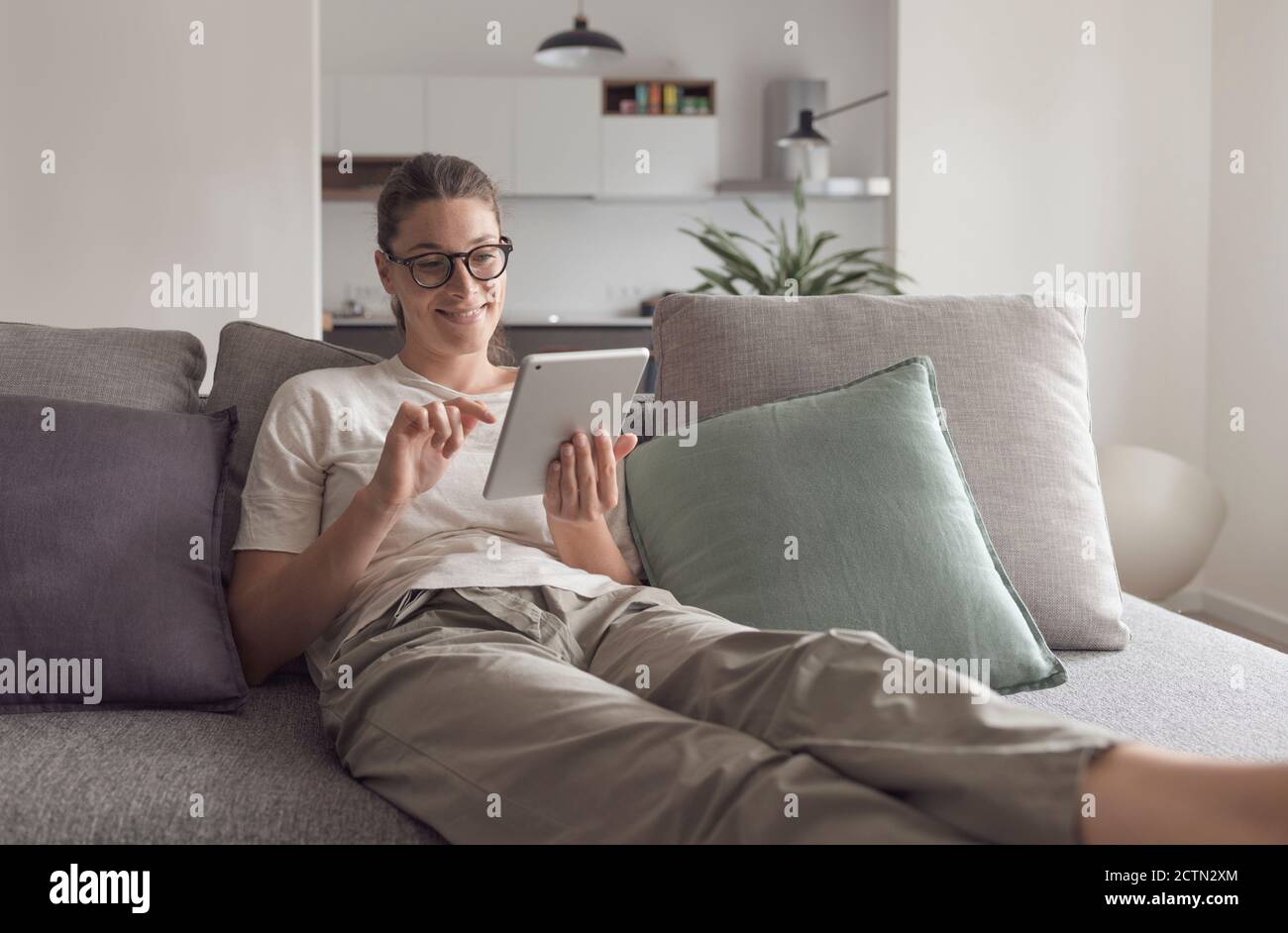 Woman relaxing on the sofa and connecting with her tablet in the living room Stock Photo