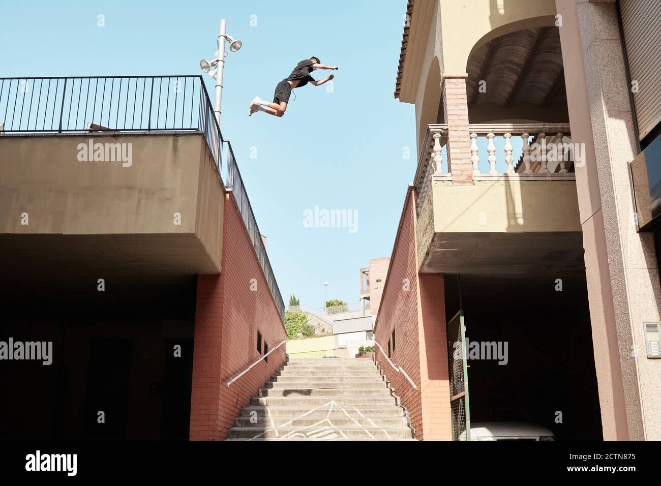 From below side view of strong male doing parkour and jumping from