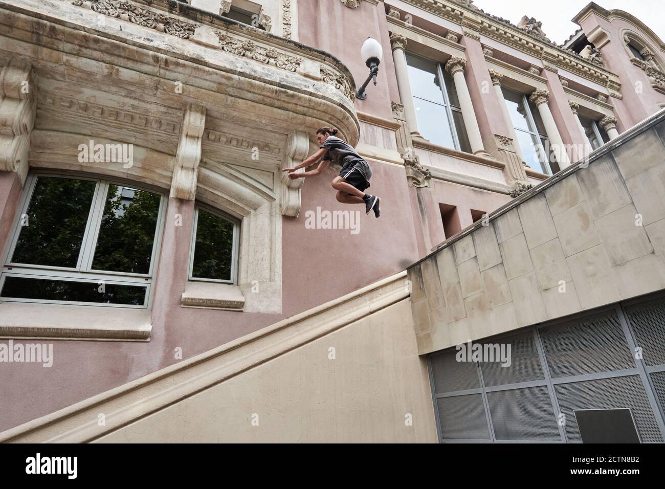 Focused young male jumping over stone steps in city while doing parkour and showing trick Stock Photo