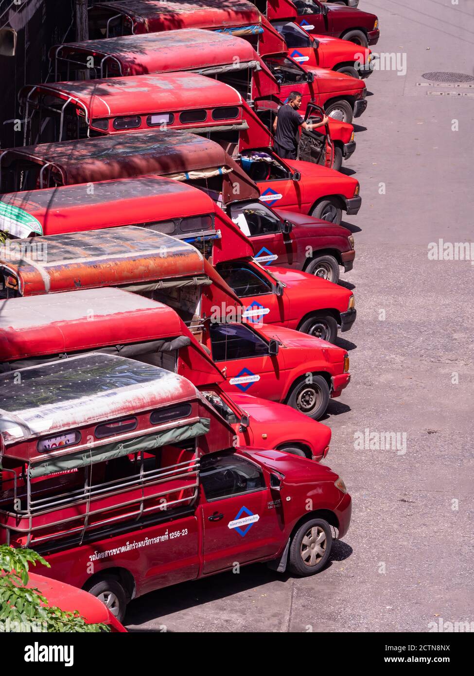 Baht buses, pickup trucks with two benches in the back, waiting for departure at Saphan Taksin in Bangkok, Thailand. The name in Thai language for the Stock Photo