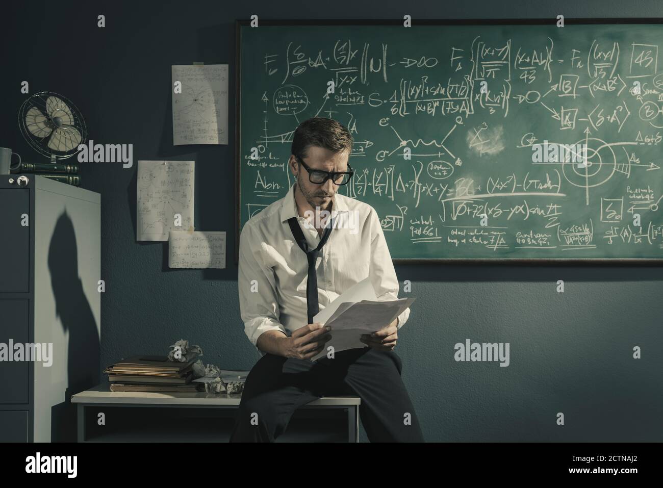 Young researcher studying mathematics in his office, he is checking ...
