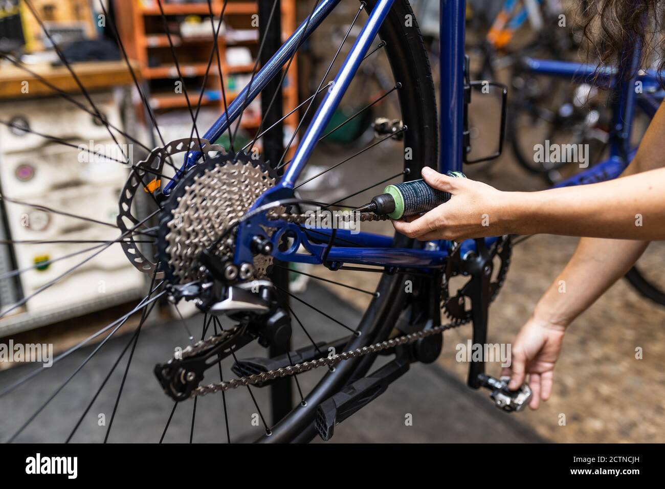 Crop anonymous mechanic putting oil on chain of bicycle while