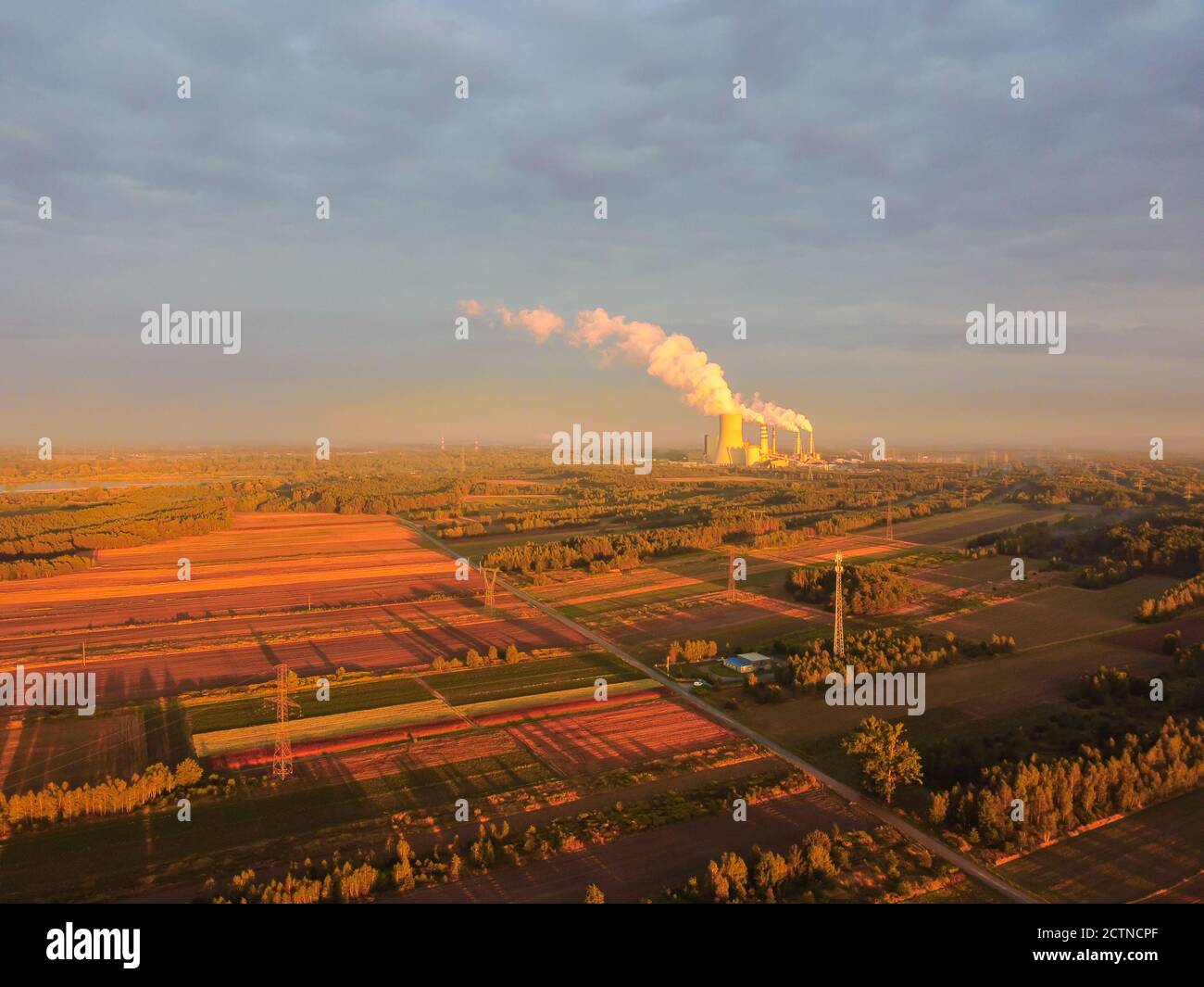 Agricultural fields with large power plant in a distance. Drone, aerial view. Stock Photo