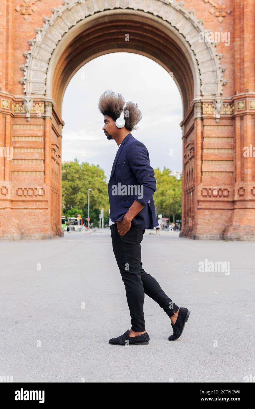 Side view of black man with afro hair and a casual suit walking down ...