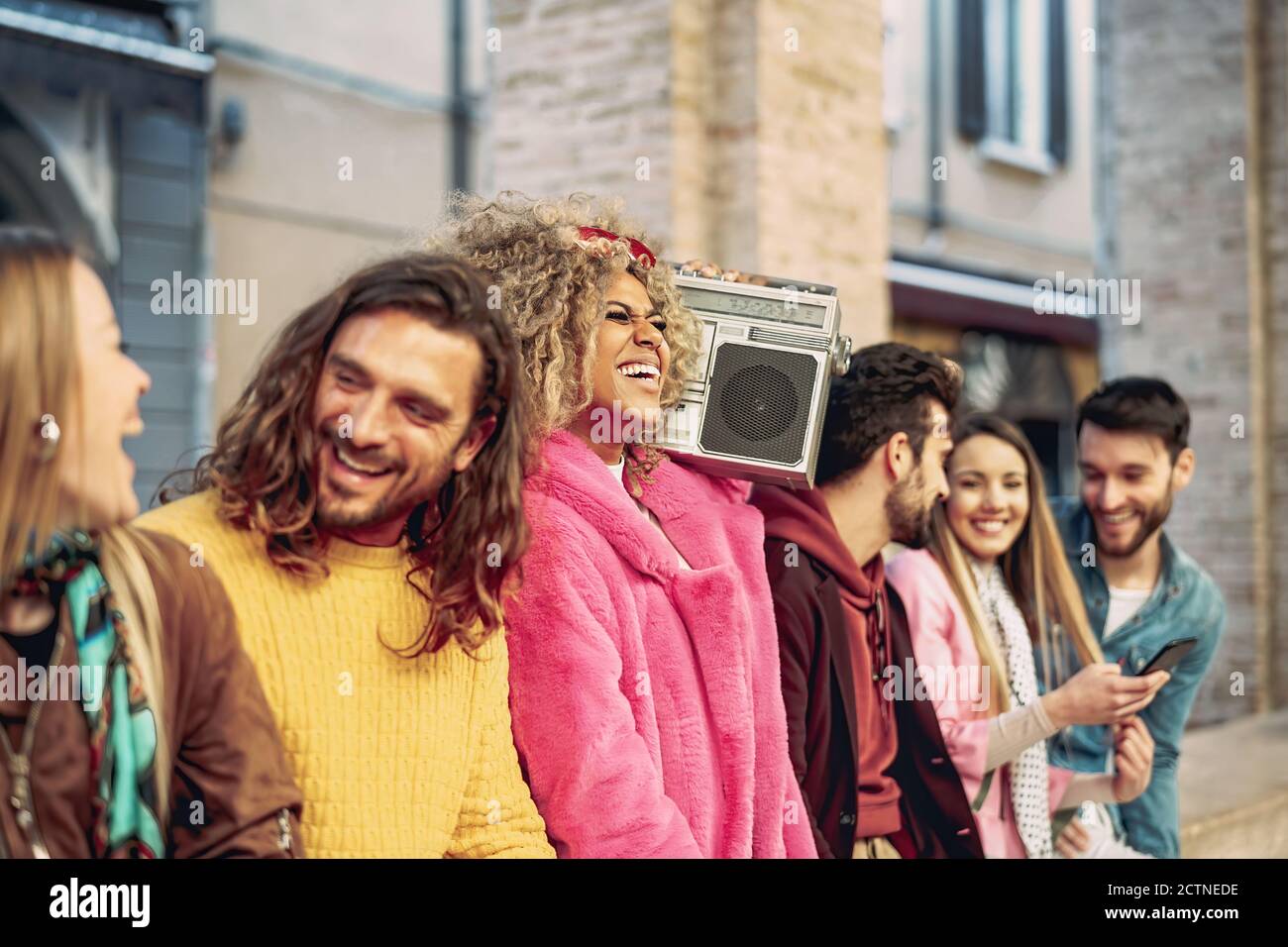 Group of friends having fun listening music with vintage boombox - Happy young people making party outdoor Stock Photo
