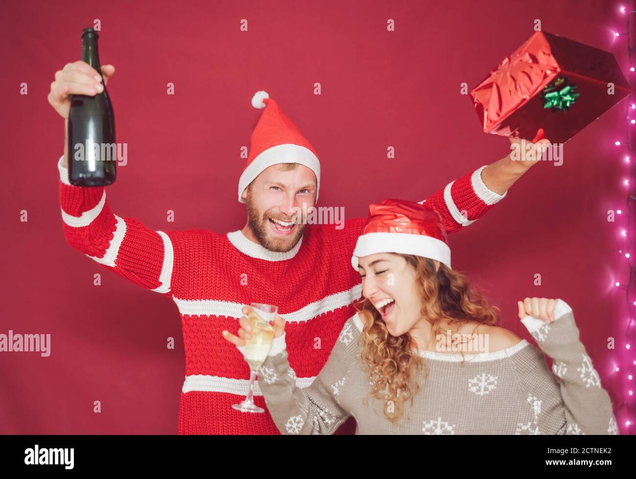 Happy couple celebrating Christmas holidays - Young people having fun drinking and laughing during xmas event Stock Photo