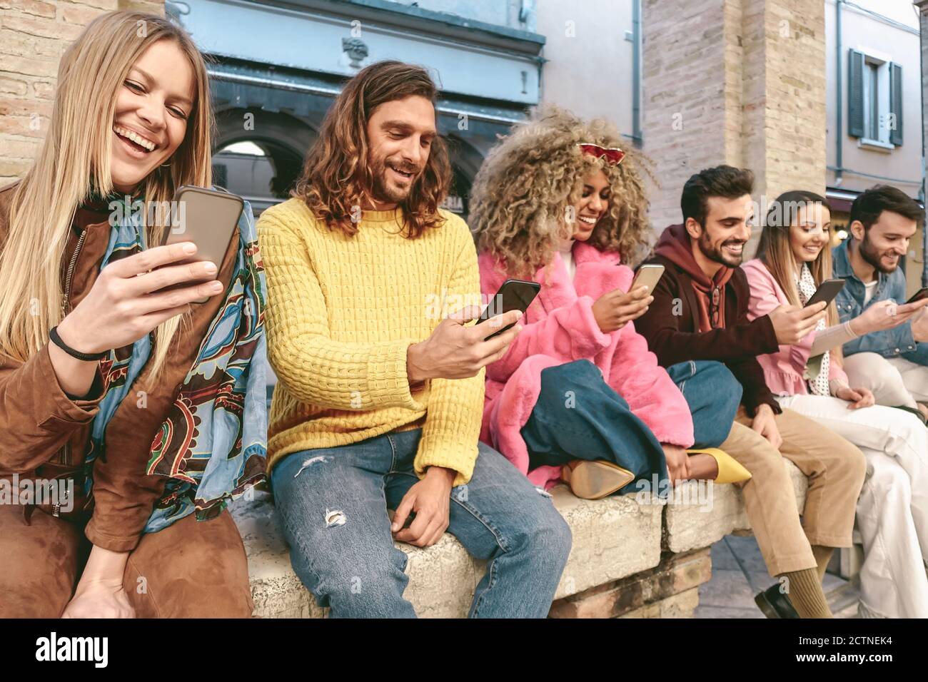 Group friends using mobile smartphone outdoor - Trendy young people having fun with new technology apps for social media phone Stock Photo