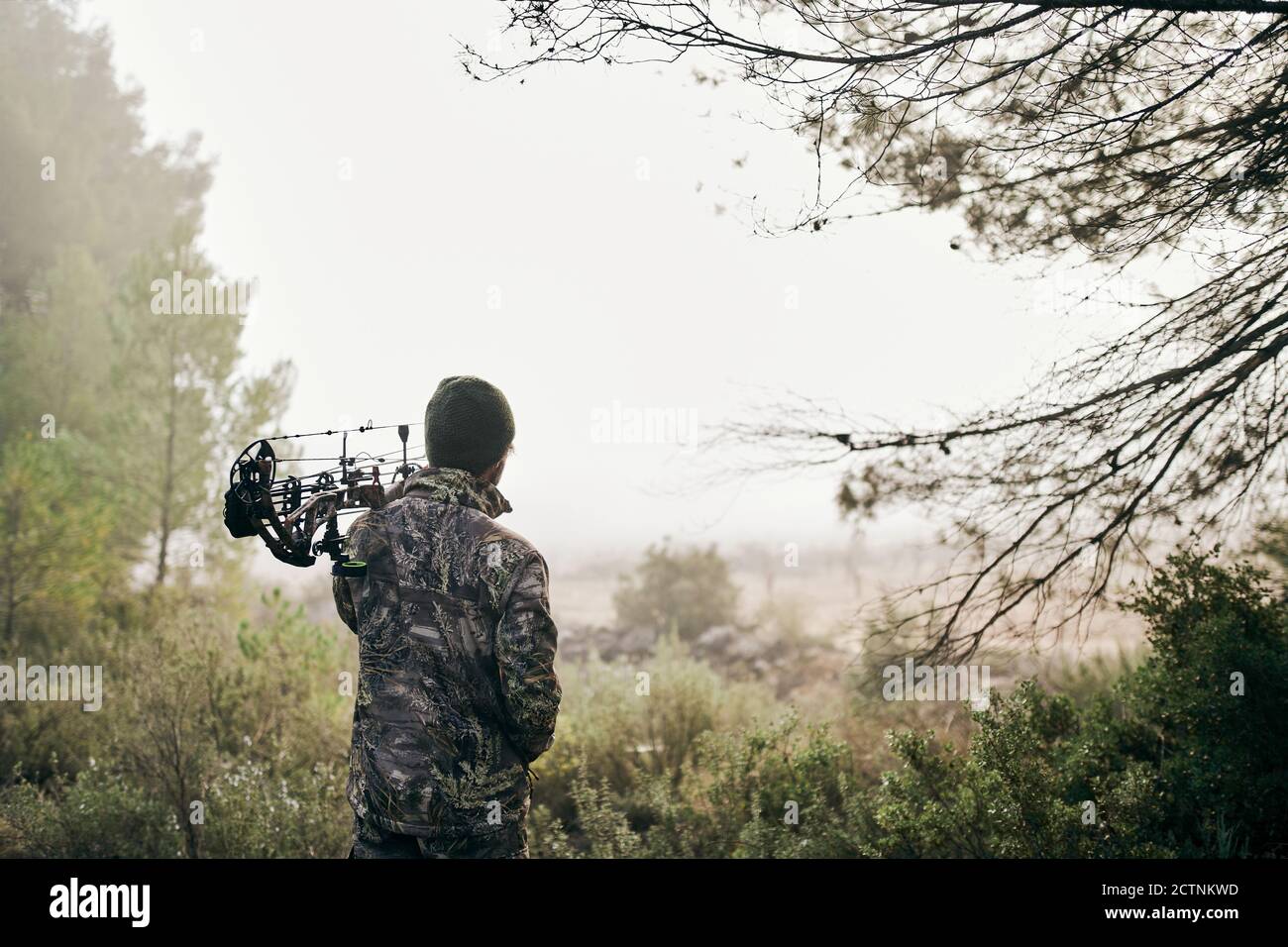 Back view of unrecognizable man in camouflage standing with compound ...
