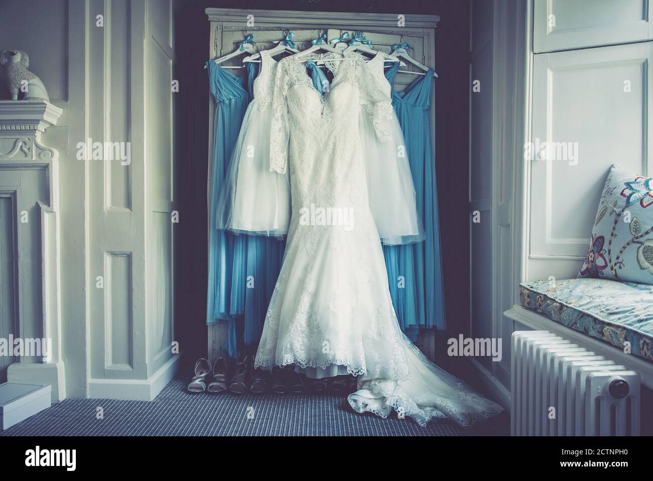 Wedding dress hanging over bridesmaid dresses and shoes Stock Photo - Alamy