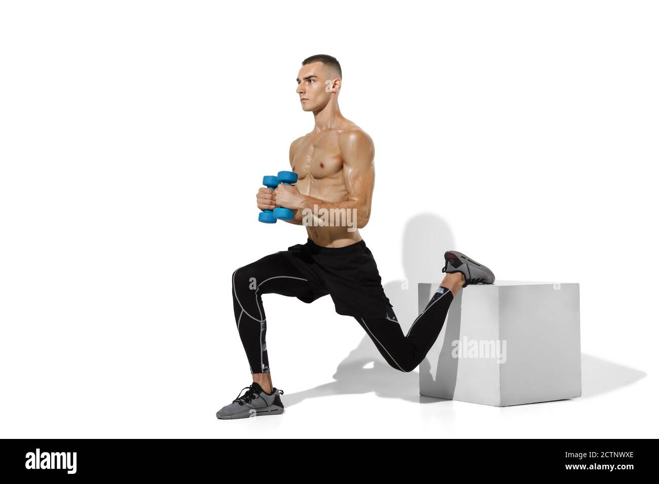 Jumpbox. Stylish young male athlete practicing on white studio background, portrait with shadows. Sportive fit model in works out in motion and action. Body building, healthy lifestyle, style concept. Stock Photo