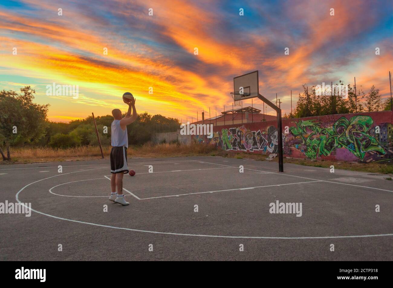Basketball player shooting and training in city playground at