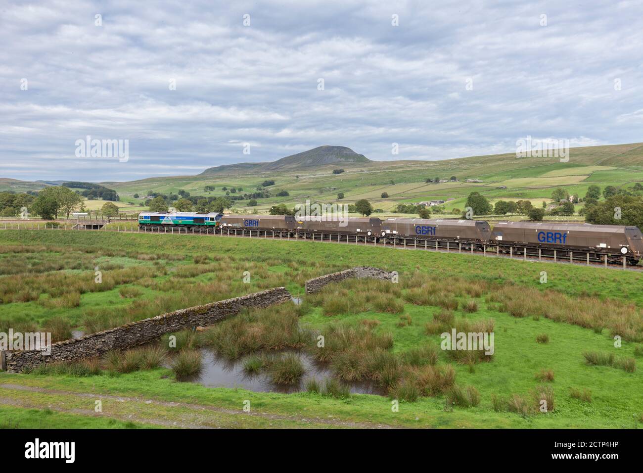 GB Railfreight class 66 locomotive 66711 departing from  the siding at Arcow Quarry, Yorkshire with a train of aggregates. Pen-y-ghent is behind Stock Photo