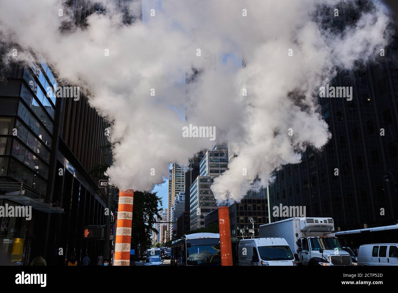 Photo of steam vapor being vented through orange and white stacks in midtown Manhattan, NYC. Stock Photo