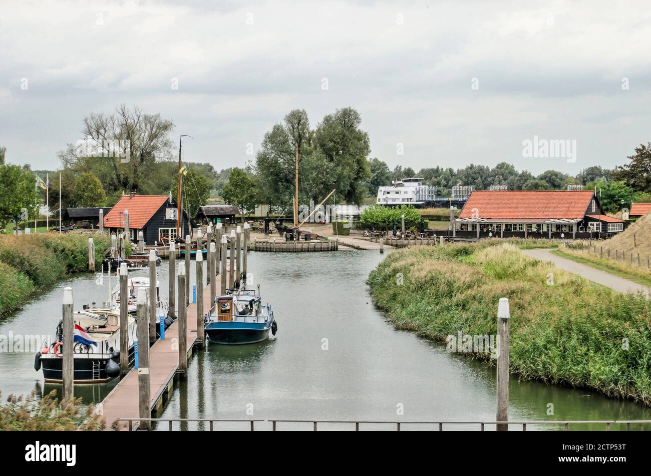 Woudrichem, The Netherlands, September 23, 2020: canal as part of the town's fortifications, with a small marina, wooden buildings and a large vessel Stock Photo