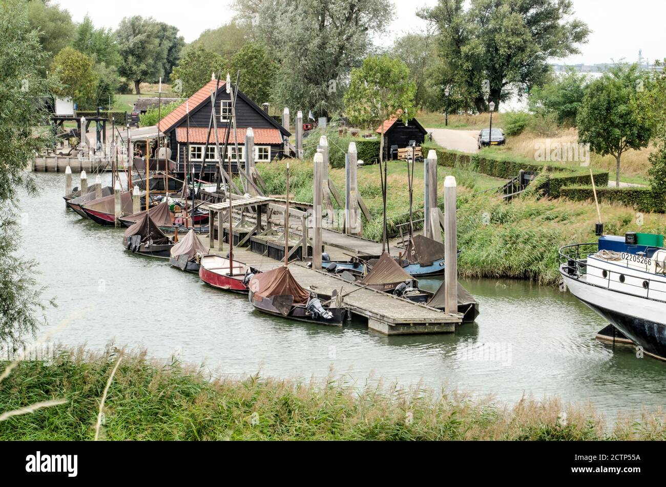 Woudrichem, The Netherlands, September 23, 2020: view of wooden buildings and a pier with small boat in a canal with green banks just outside the old Stock Photo