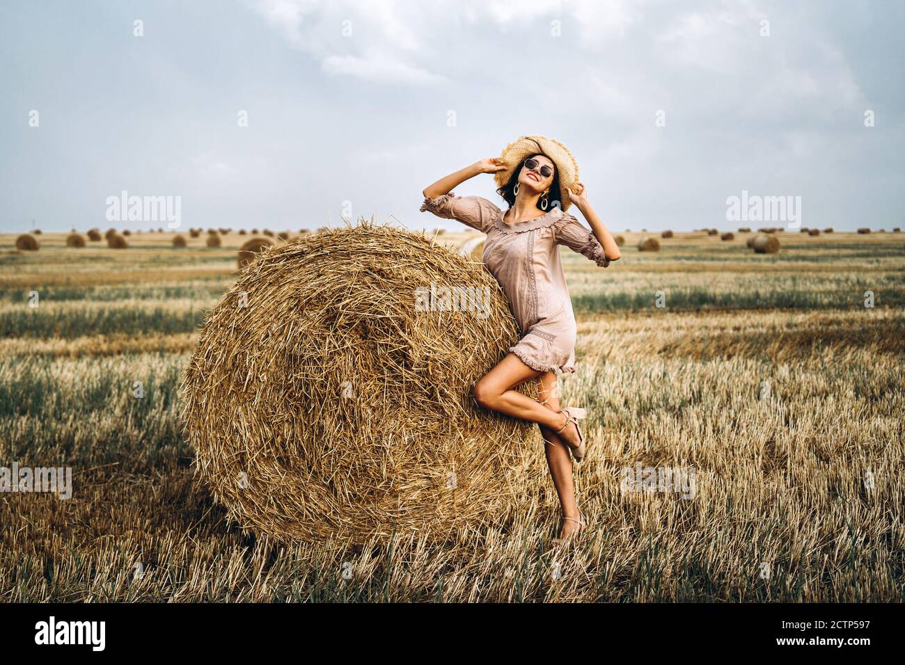 Beautiful young girl with long hair in sunnglasses and straw hat posing ...