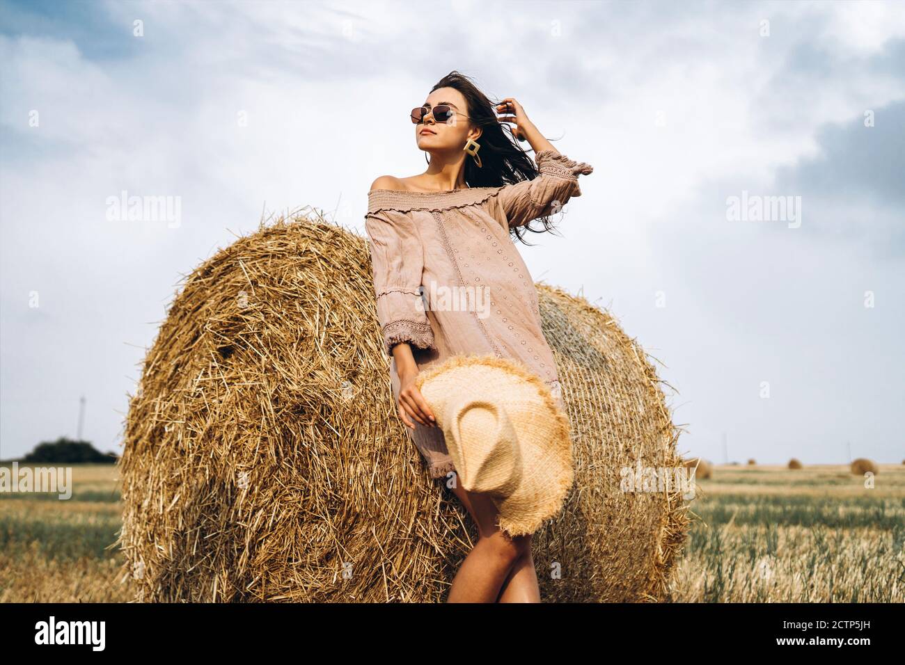 Beautiful young girl with long hair in sunnglasses and straw hat posing ...
