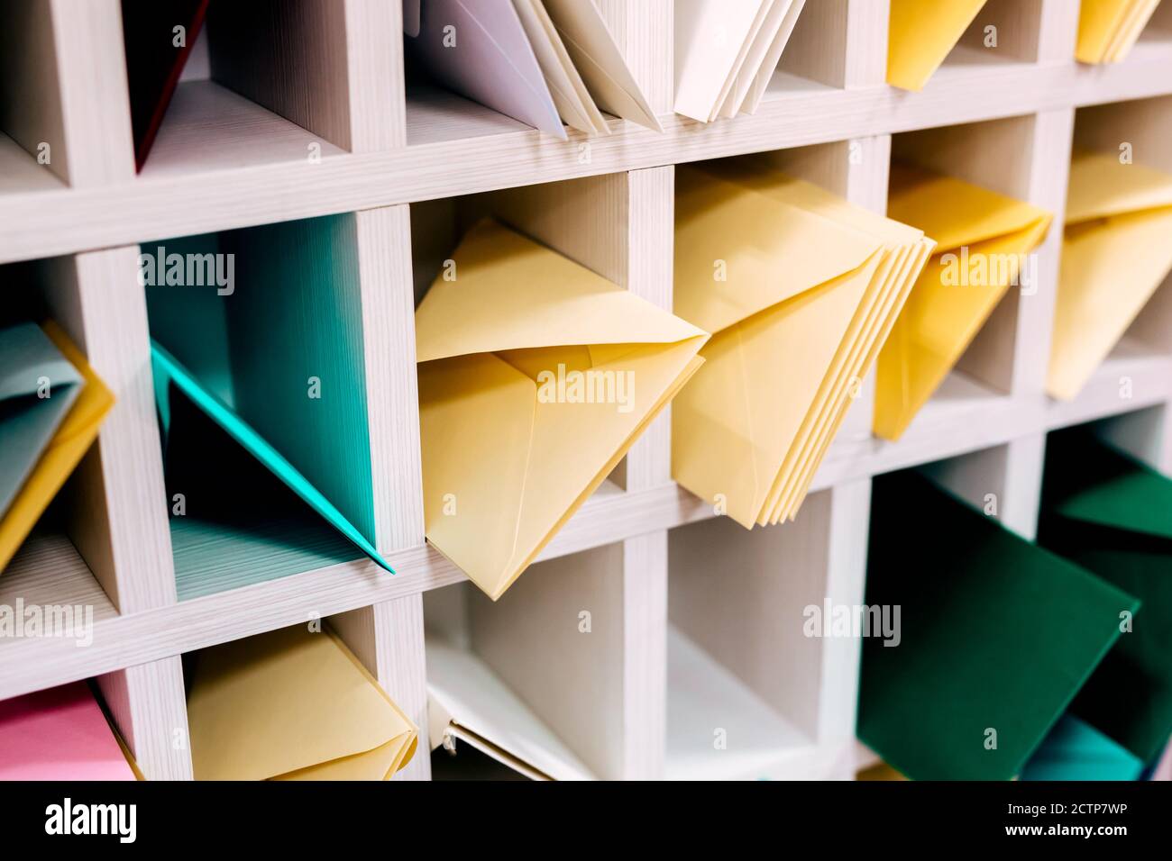 Various sort mail envelopes arranged on a shelf by color and type categories. Stock Photo