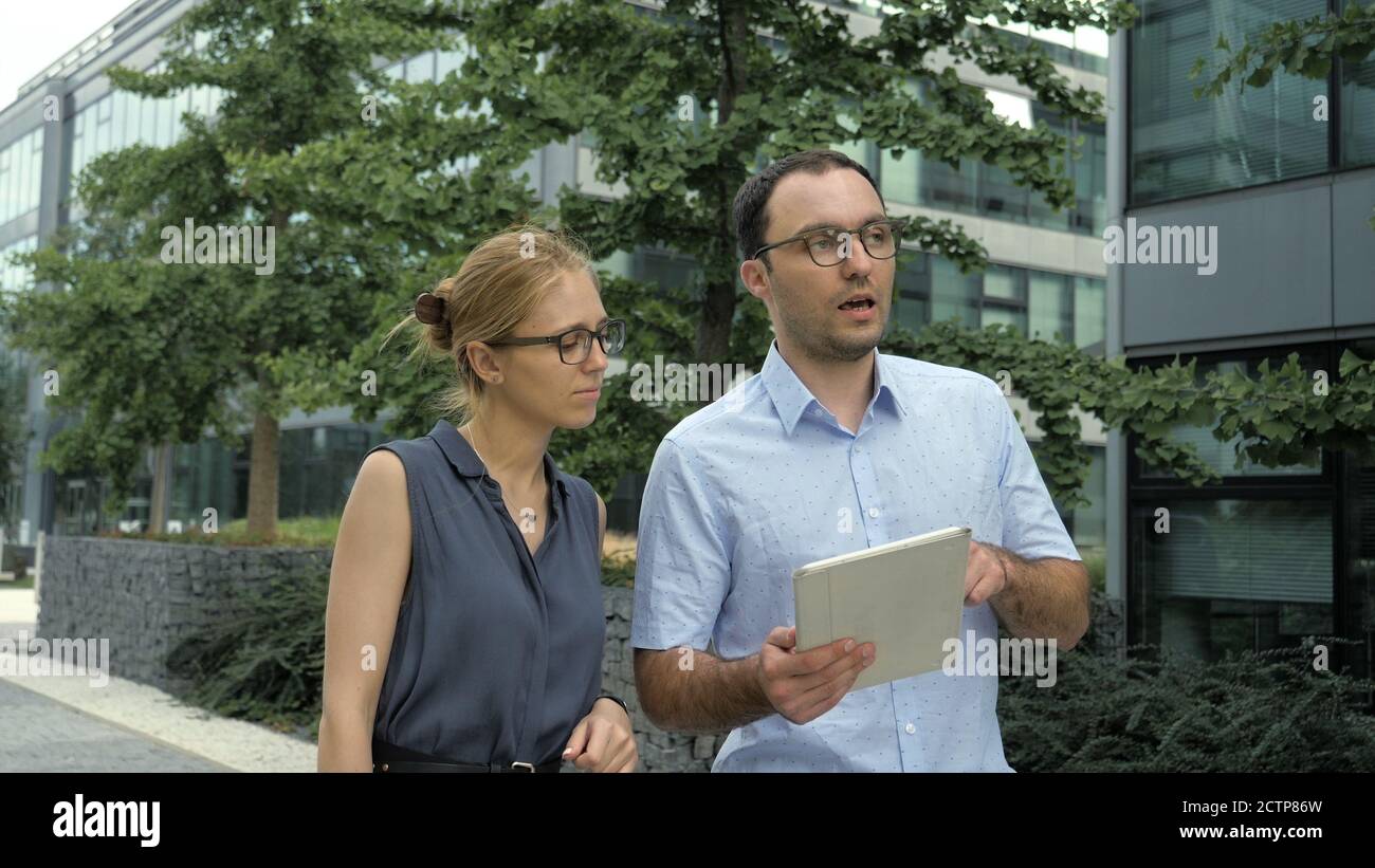 Female and Male Business People Walking Talking and Using Tablet Stock Photo