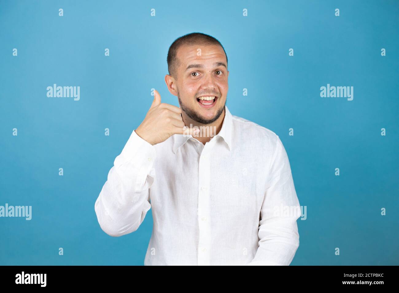 Russian business man over blue background smiling doing phone gesture with hand and fingers like talking on the telephone Stock Photo