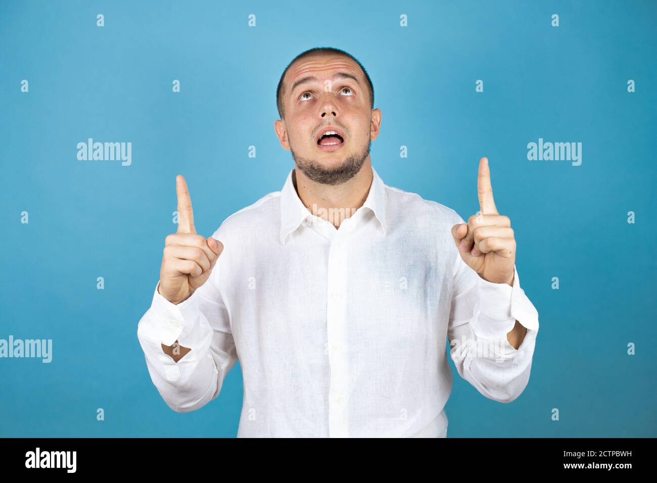 Russian business man wearing white shirt standing over blue background smiling with happy face pointing up with two fingers Stock Photo