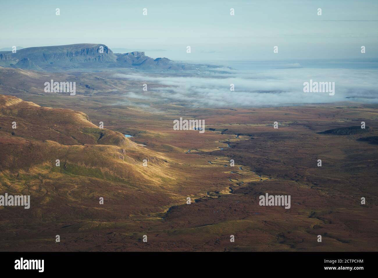 A top view of an autumn mountain valley with winding river and the sea covered with low clouds at dawn. The Isle of Skye, Scotland, UK Stock Photo