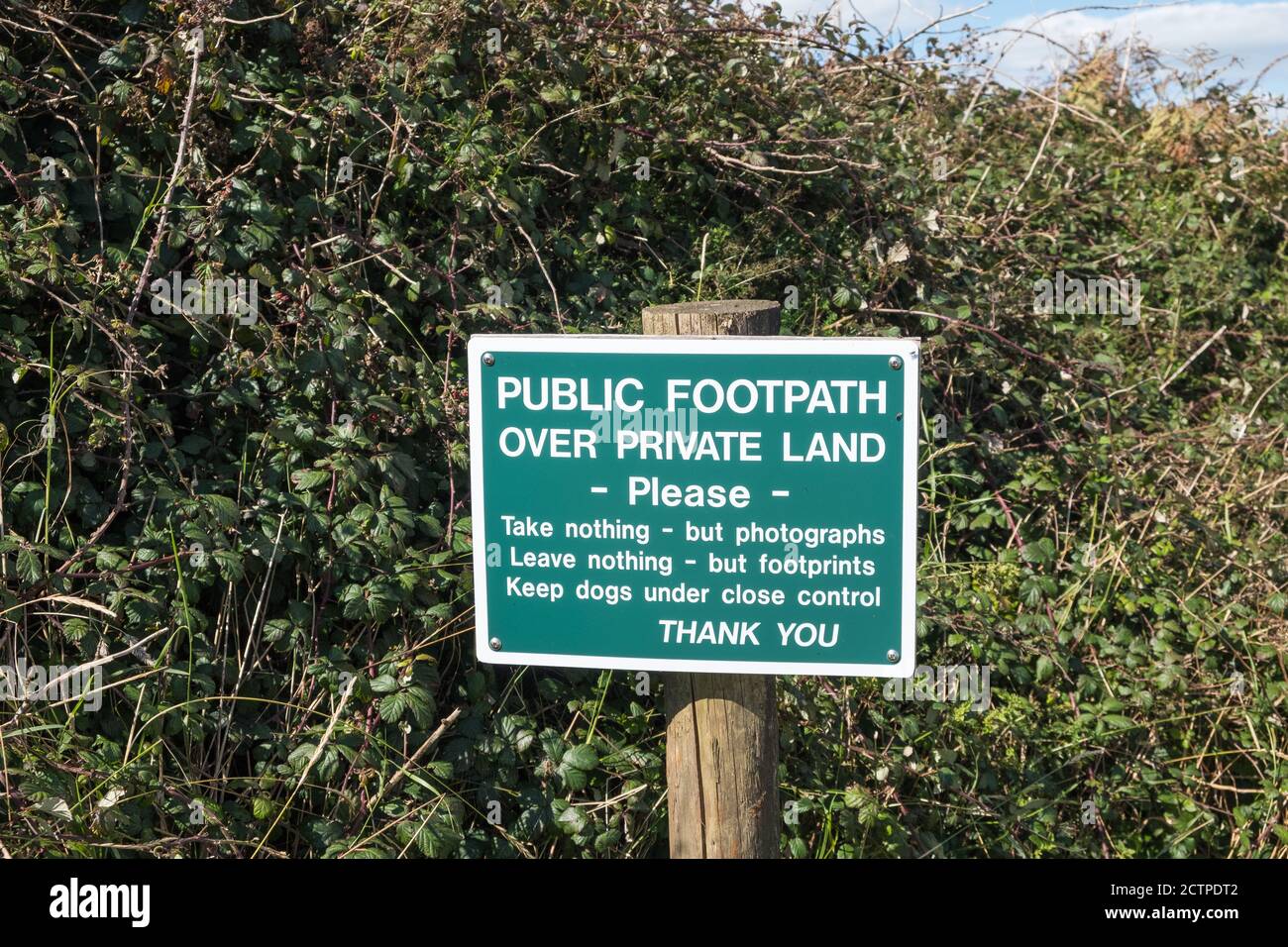 Sign saying public footpath over private land on the South West Coastal Path near Salcombe in the South Hams, Devon, UK Stock Photo