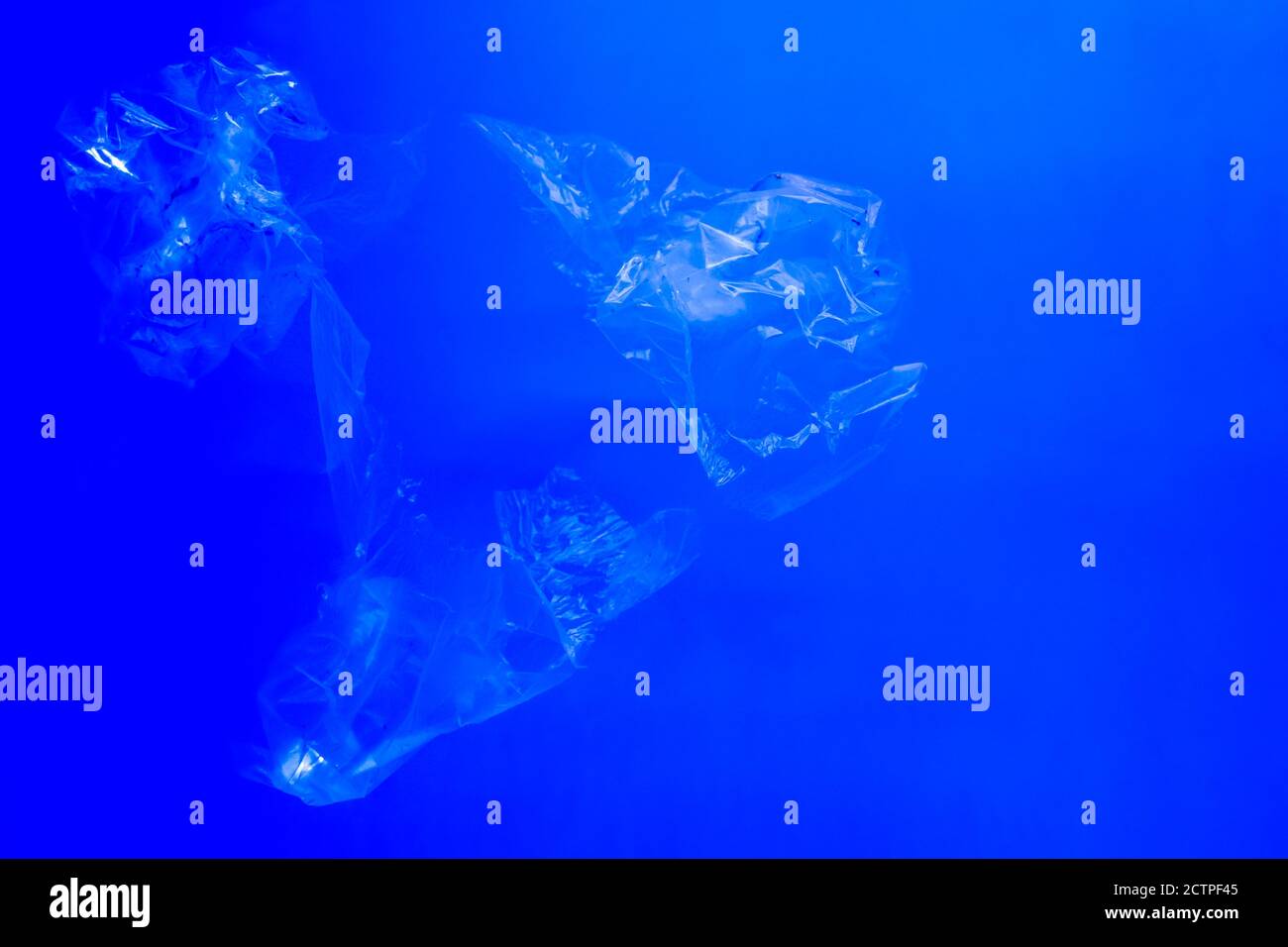 Transparent plastic bags floating underwater in blue ocean sea water, pollution by non-biodegradable plastic waste, hazard for marine wildlife Stock Photo