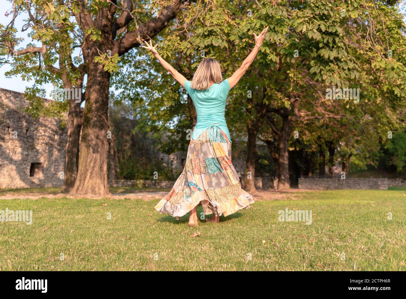 Beautiful barefoot girl in a long colorful skirt is dancing in natural background Stock Photo