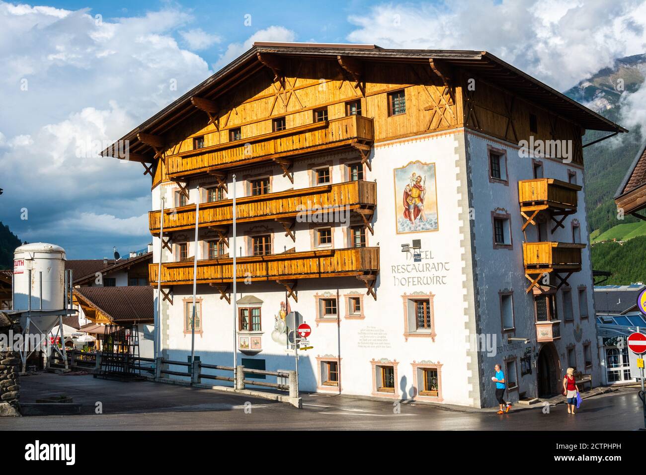 Neustift im Stubaital, Austria – May 31, 2017. Historic building, currently housing Hoferwirt hotel and restaurant, in Neustift, with people. Stock Photo