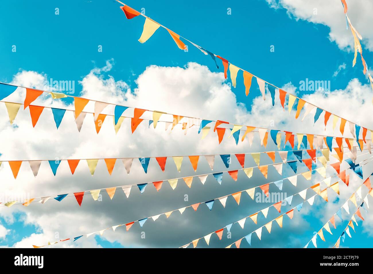 Colorful bright triangular Bunting flags on a blue sky background with ...