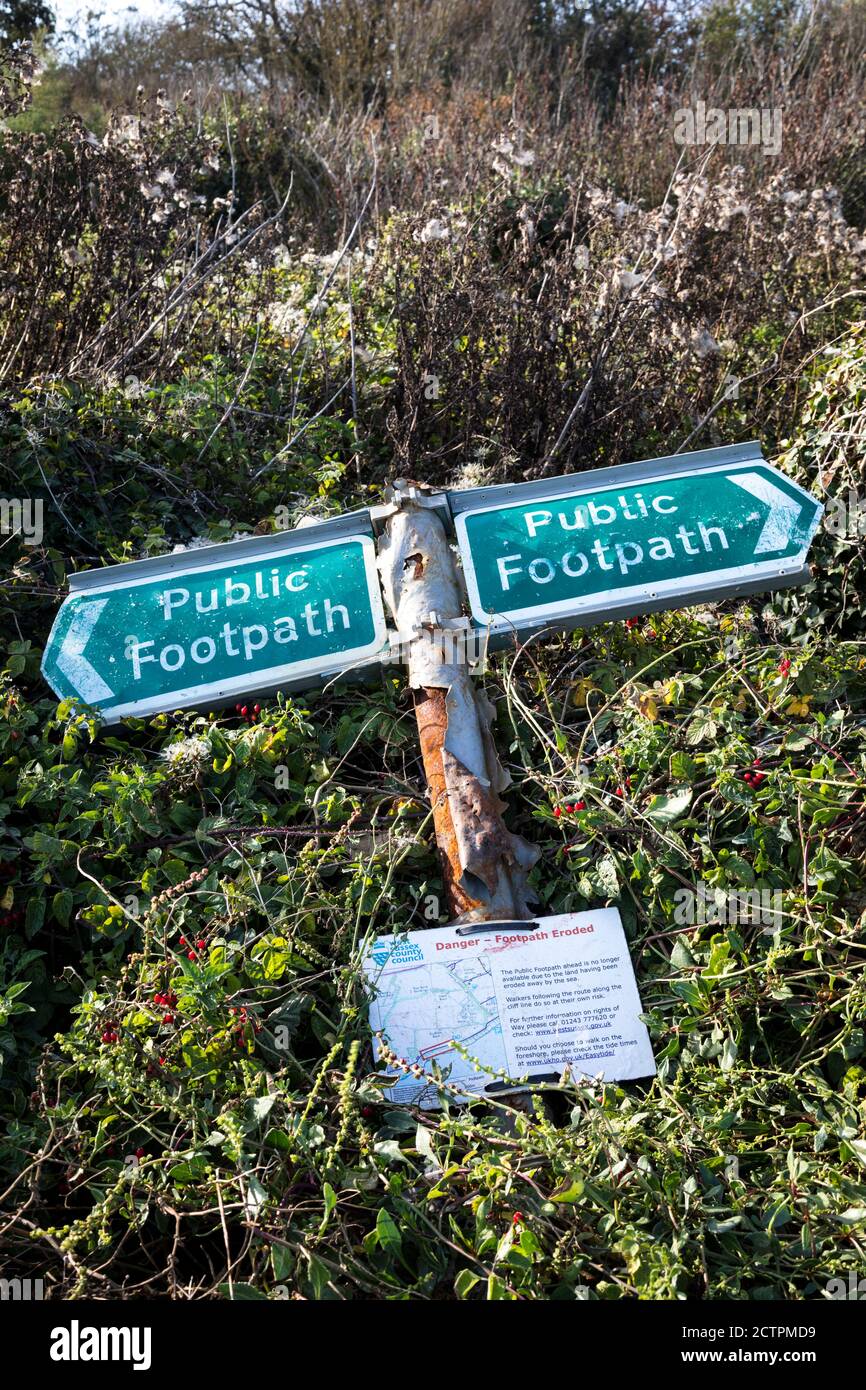Old broken metal green Public Footpath sign lying against brambles, West Sussex. Stock Photo