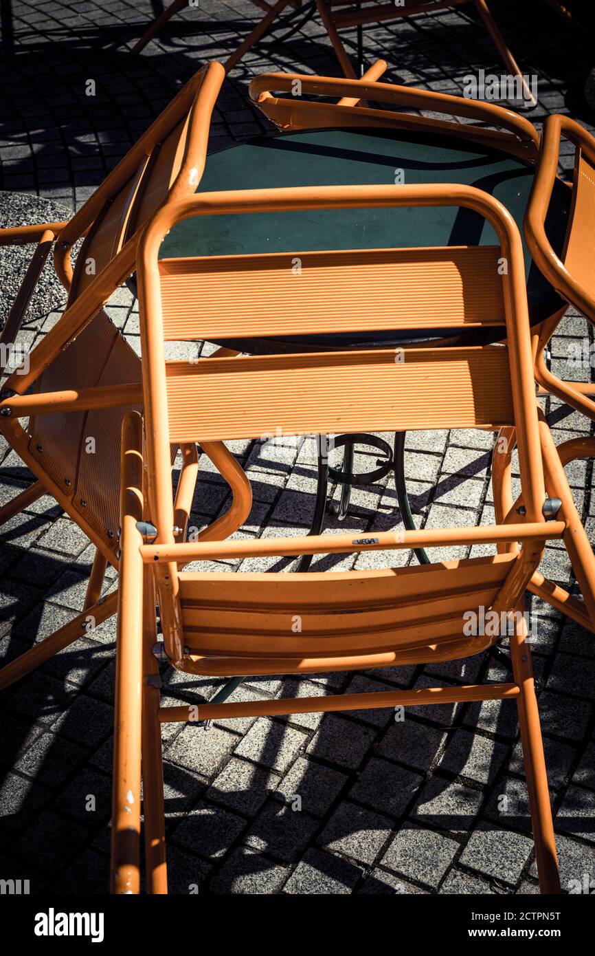 Orange metal café chairs leaning on a table, Italy. Stock Photo