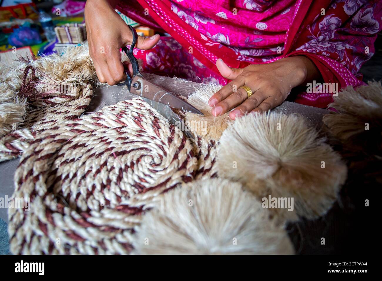 A woman making handicrafts is smoothing the fibers of a banana tree