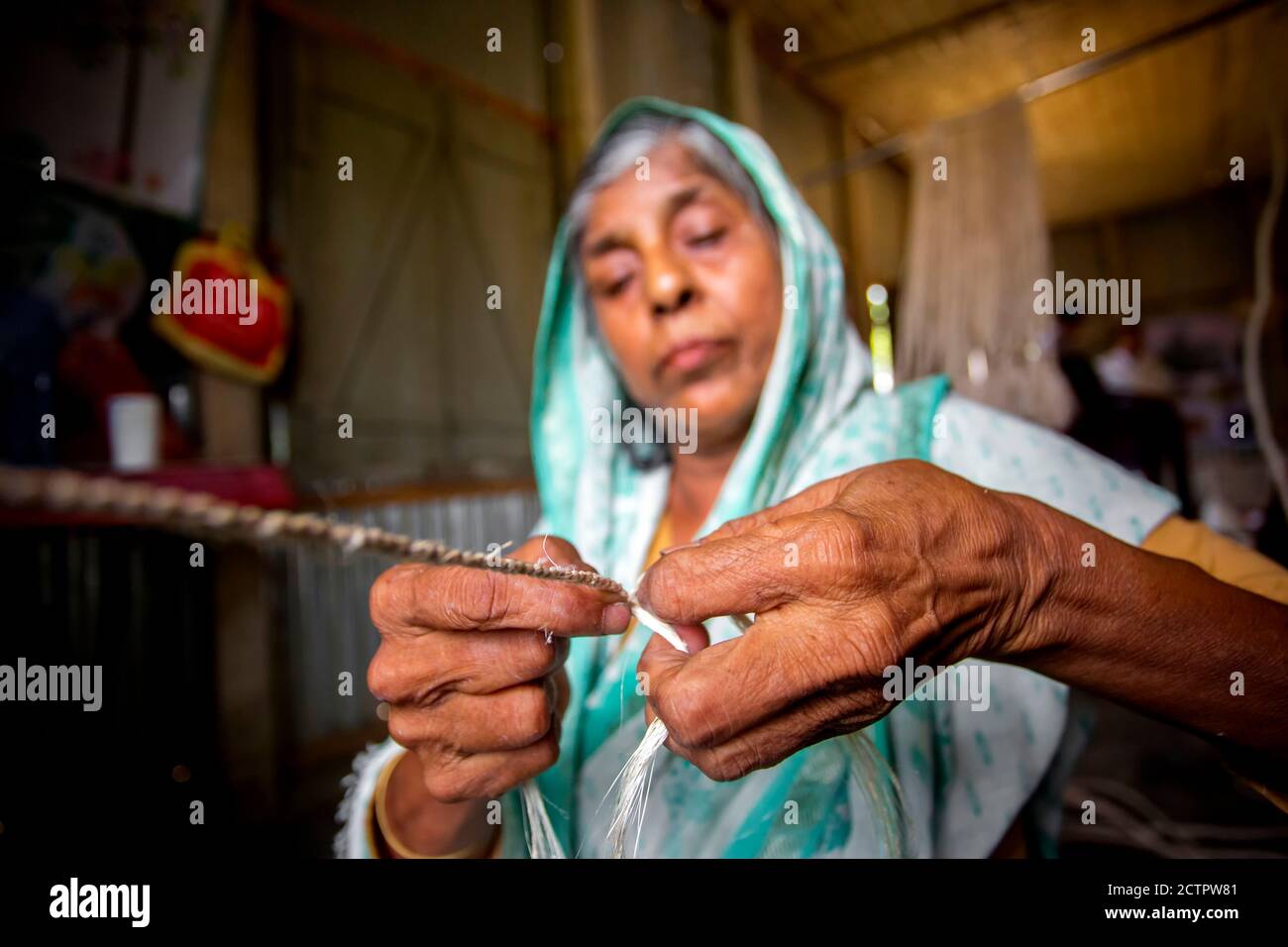 An old age woman is making on his skinny hands a rope from the banana