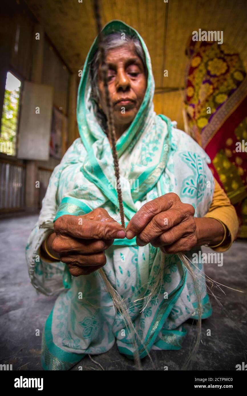 An old age woman is making on some fiber rope using on the banana tree