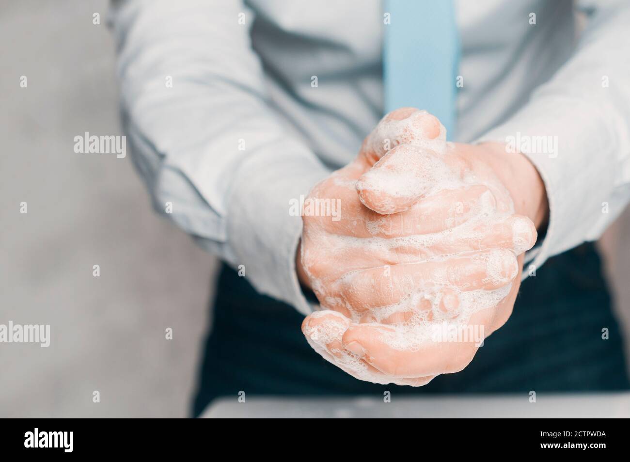 Businessman in blue shirt and tie soap his hands. Hand washing is important to avoid the risk of contagion from coronavirus. Stock Photo