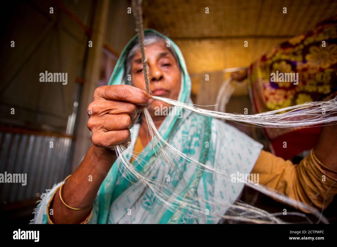 An old age woman is making on his skinny hands a rope from the banana