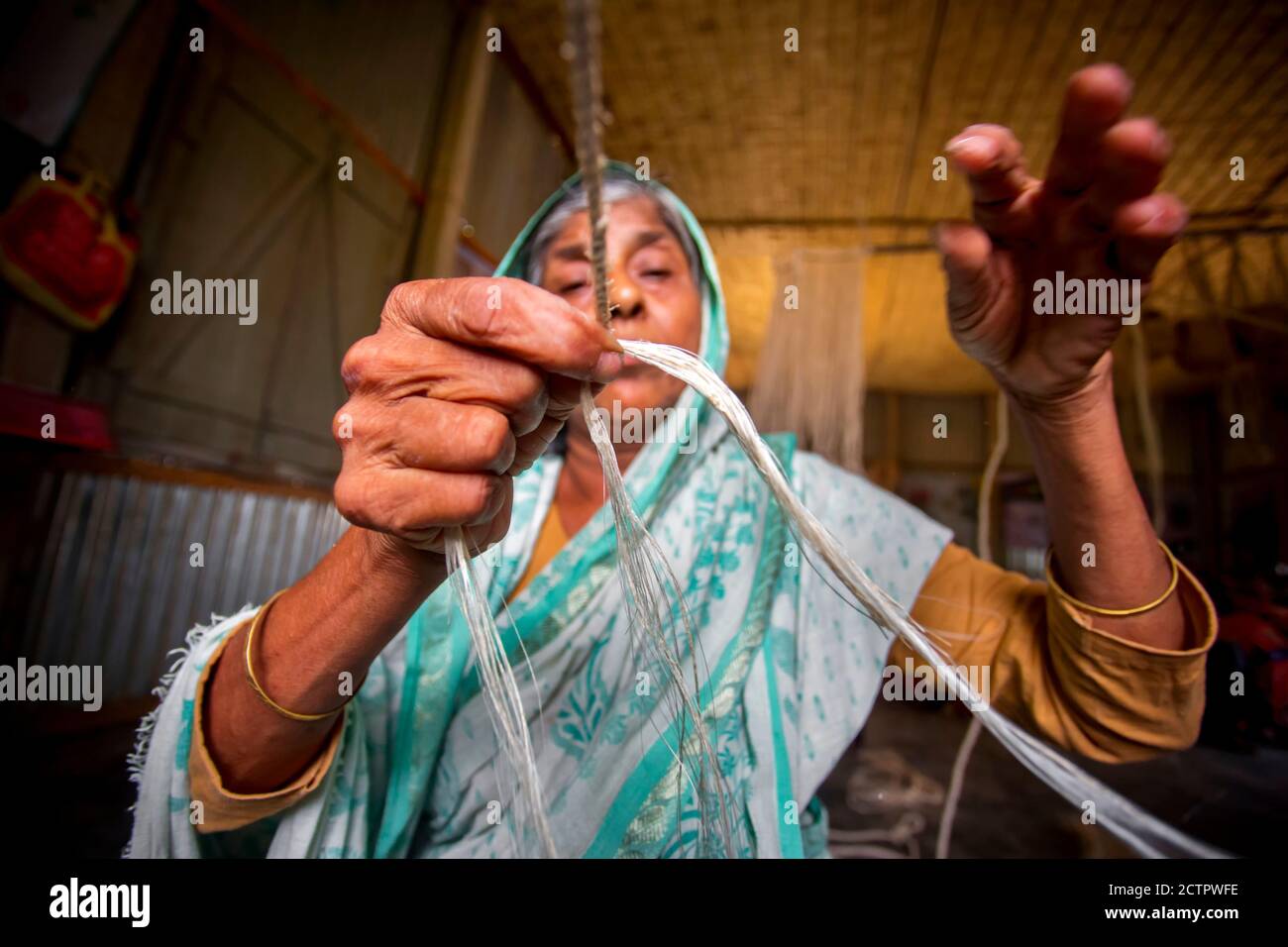 An old age woman is making on his skinny hands a rope from the banana