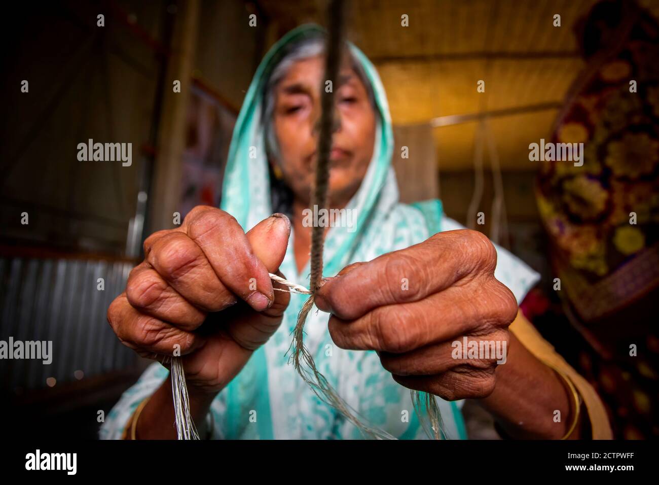 An old age woman is making on his skinny hands a rope from the banana