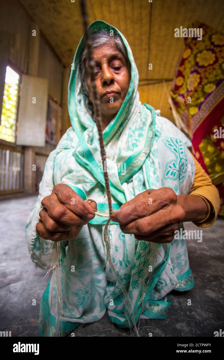 An old age woman is making on some fiber rope using on the banana tree