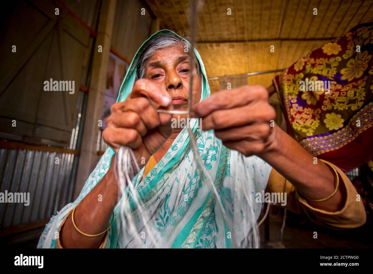 An old age woman is making on his skinny hands a rope from the banana